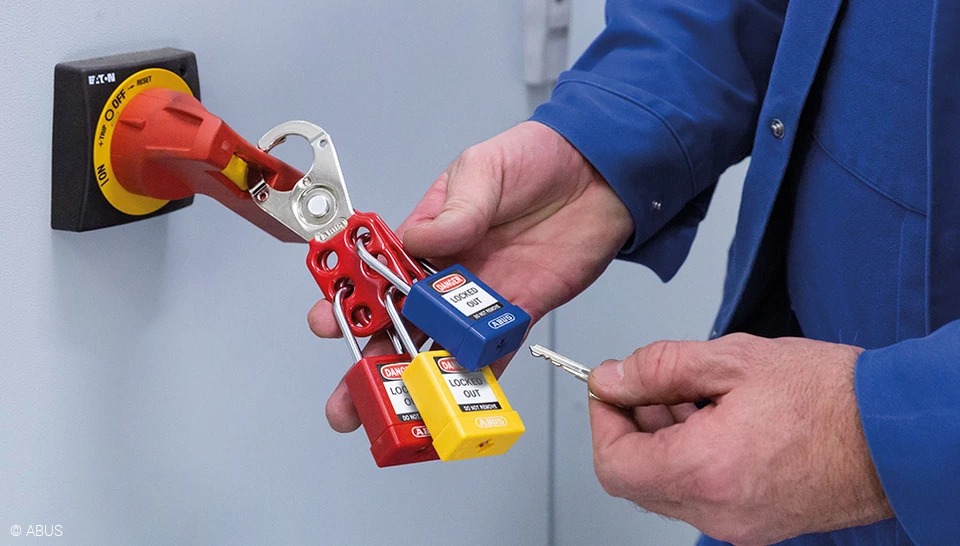 Technician applying a lockout hasp with ABUS safety padlocks to an electrical isolator
