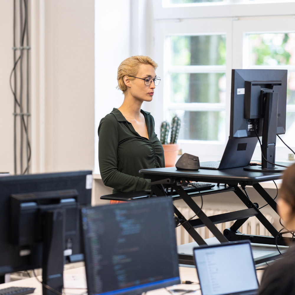 Woman working at a height-adjustable standing desk in a bright office